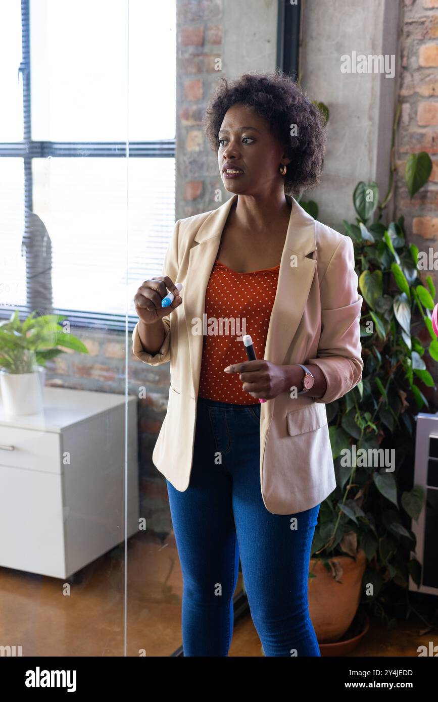 Presenting in office, woman holding markers and explaining to ...