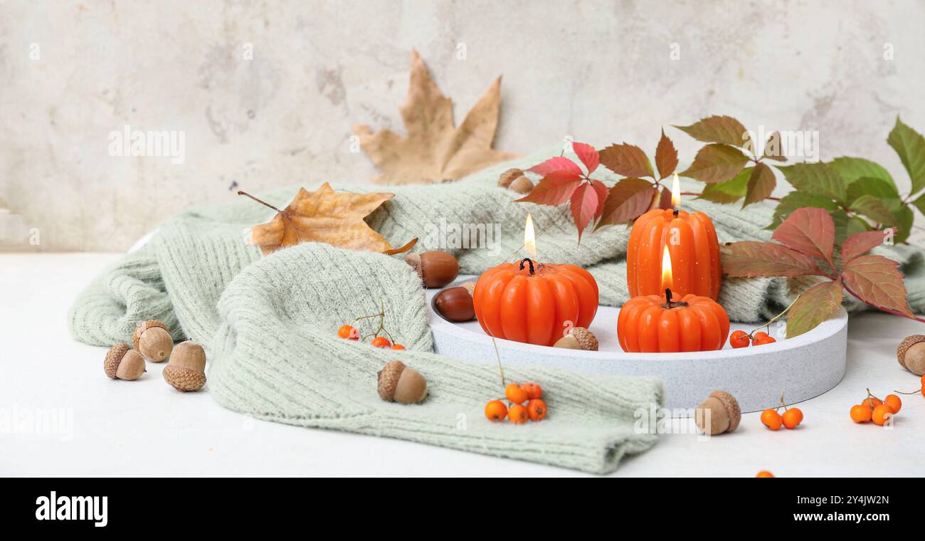 Beautiful autumn composition with burning candles in shape of pumpkins on light background Stock Photo
