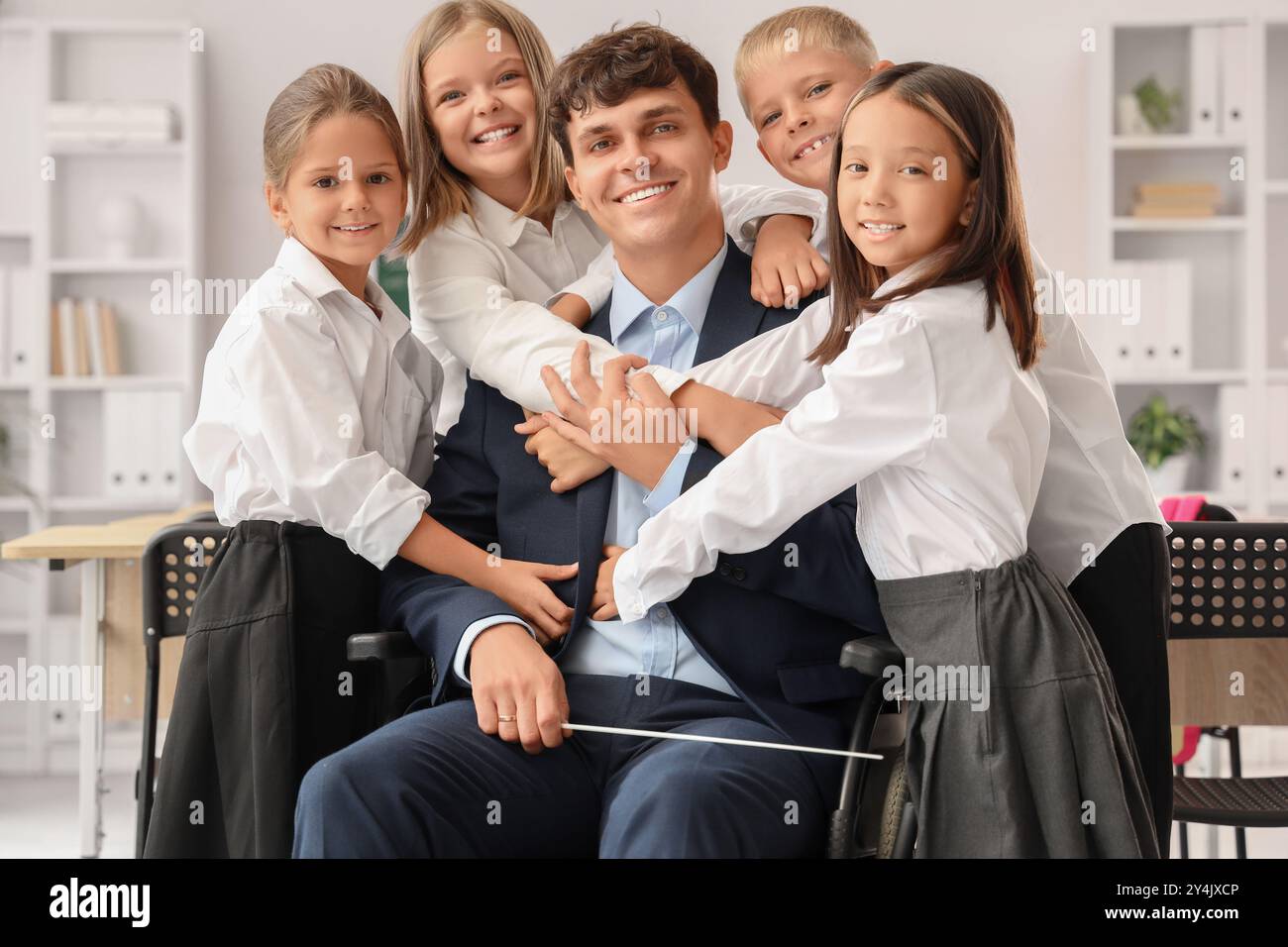 Little pupils hugging male teacher in wheelchair at school Stock Photo ...