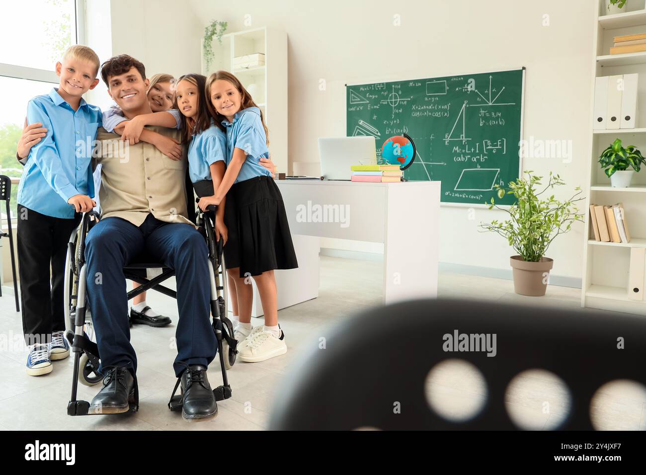 Male teacher in wheelchair hugging with little pupils at school Stock ...