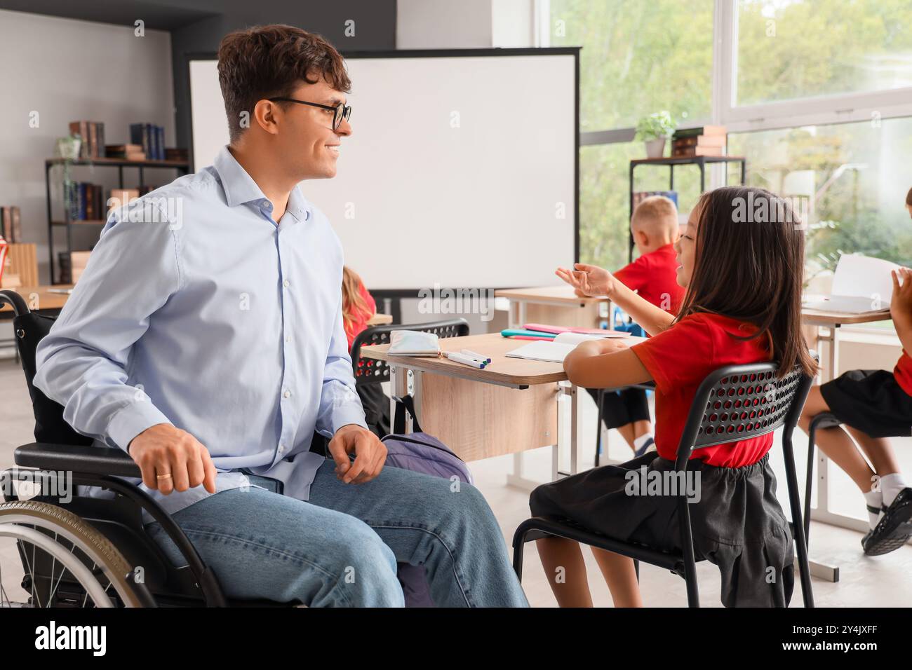 Male teacher in wheelchair conducting to little pupils at school Stock ...