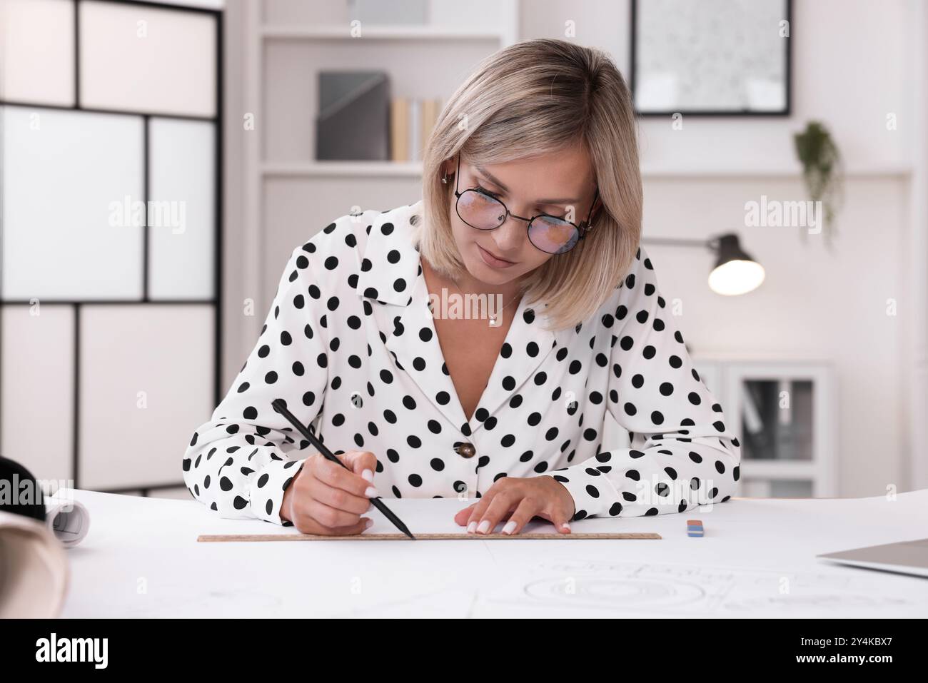 Architect making engineering drawing at table in office Stock Photo
