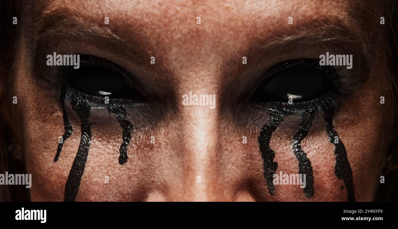 Close-up of womans eyes with pitch-black sclera and tears of darkness flowing down her cheeks. Devil Stock Photo