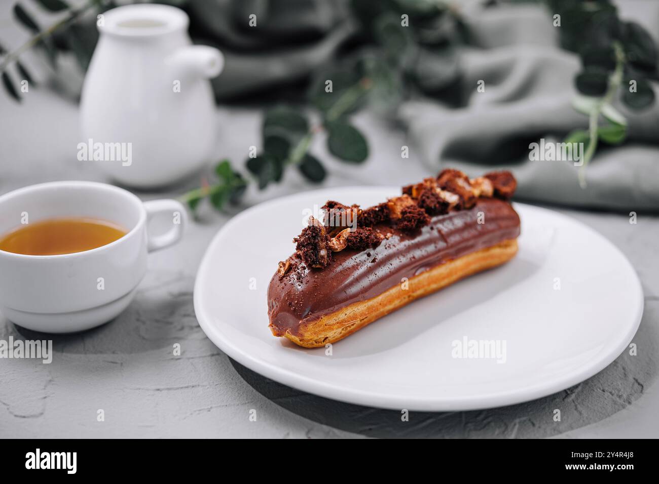 Eclair with Chocolate Cream and Hazelnuts and tea Stock Photo