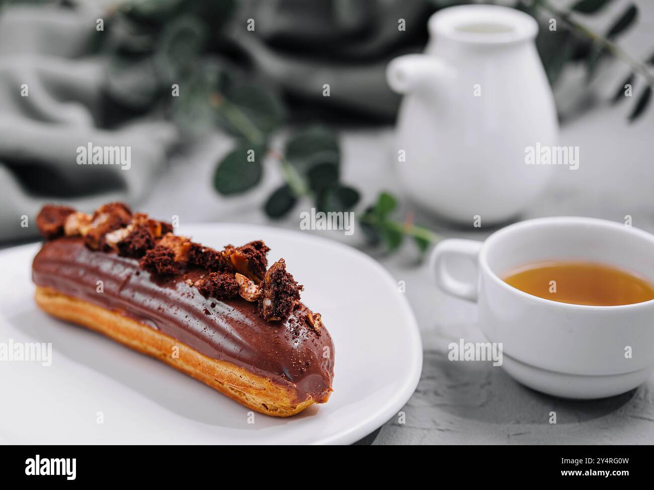 Eclair with Chocolate Cream and Hazelnuts and tea Stock Photo