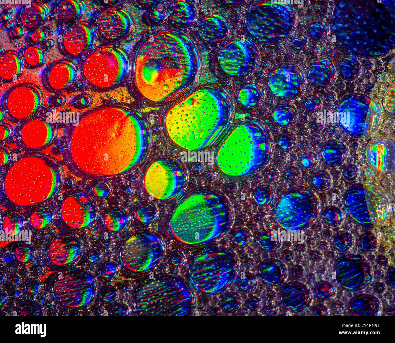 A macro shot showing patterns and colours of oil drops floating on ...