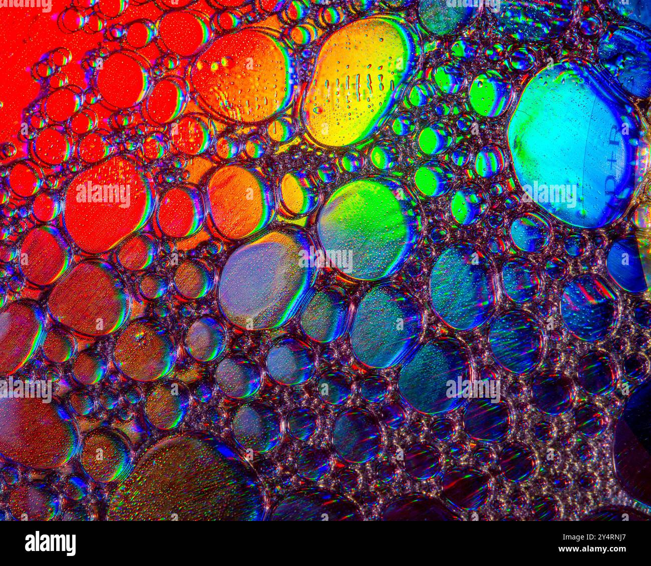 A macro shot showing patterns and colours of oil drops floating on ...