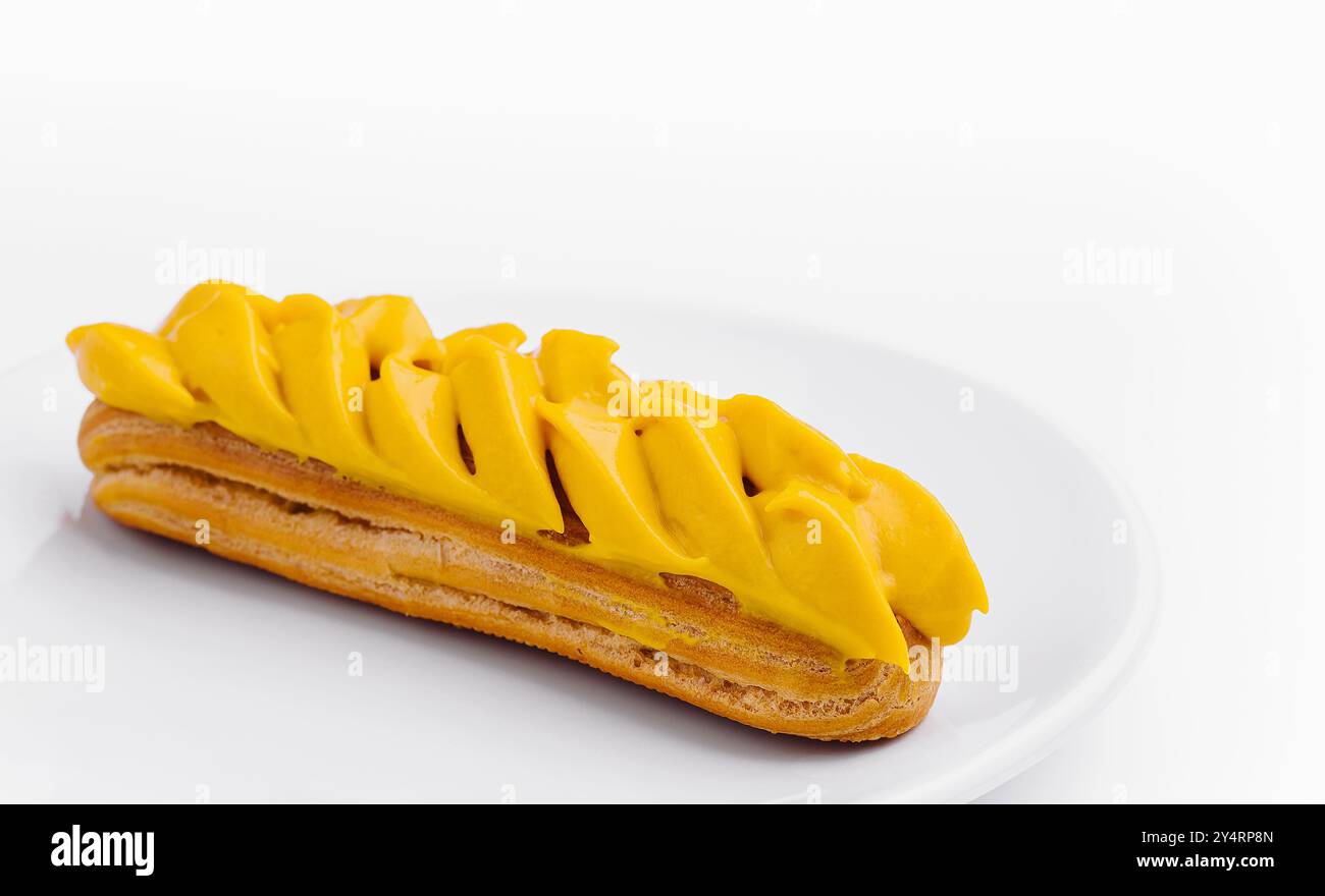 Eclair with Mango Cream on White Plate Stock Photo
