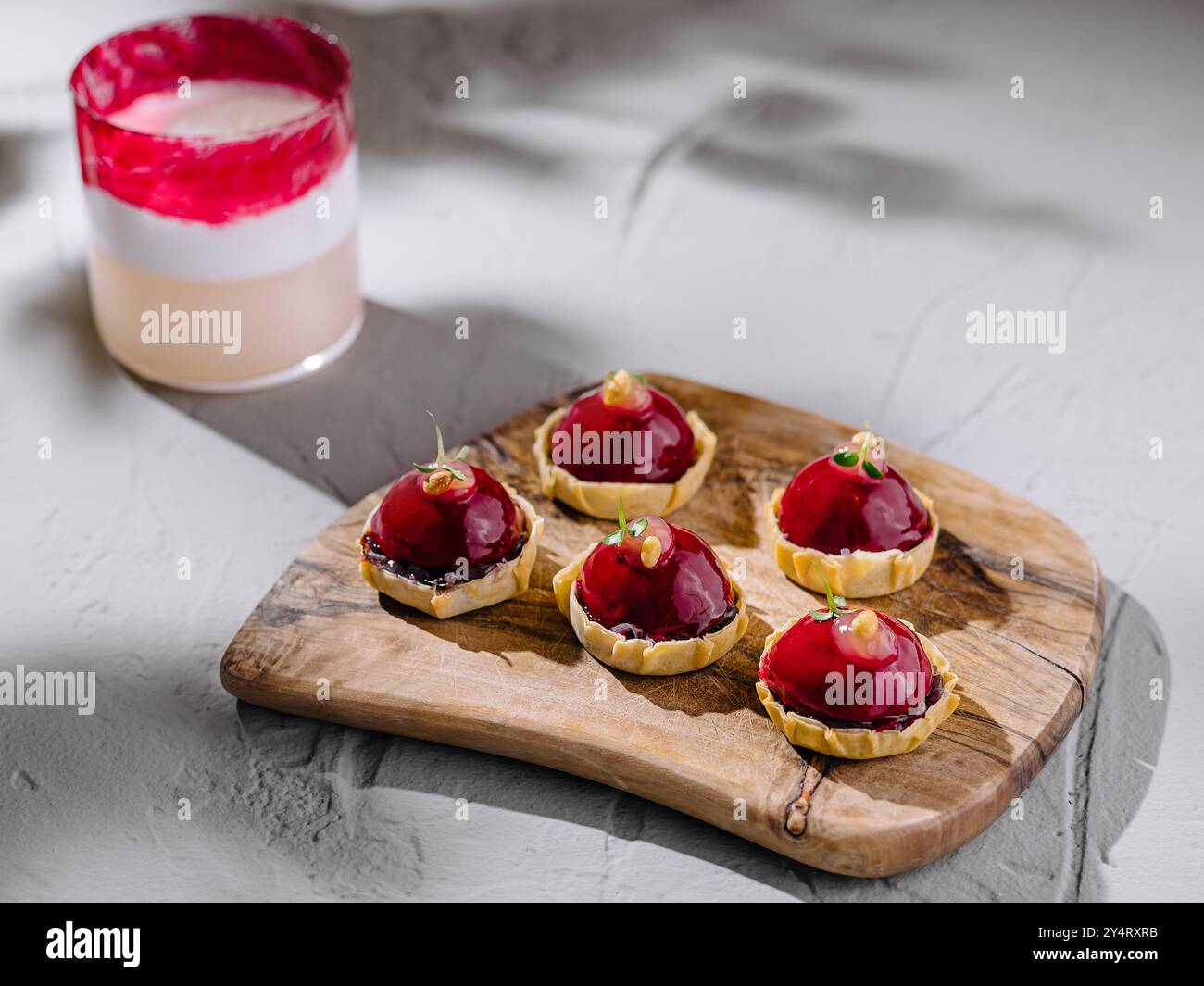 Layered Raspberry Tart Artistic display of raspberry tarts and a layered beverage on a rustic ...