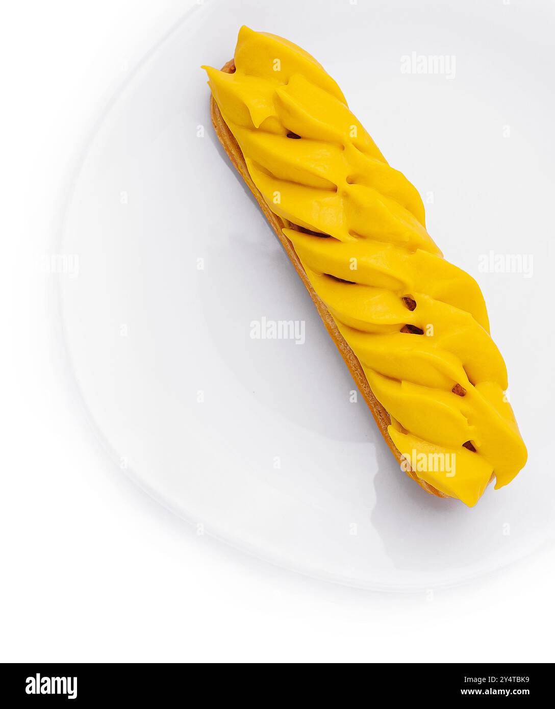 Vibrant mango eclair presented on a pure white circular plate, isolated ...