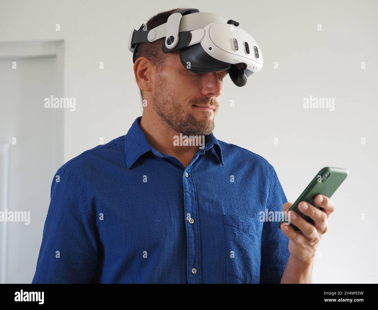 Man in Virtual Reality headset using using phone. Stock Photo