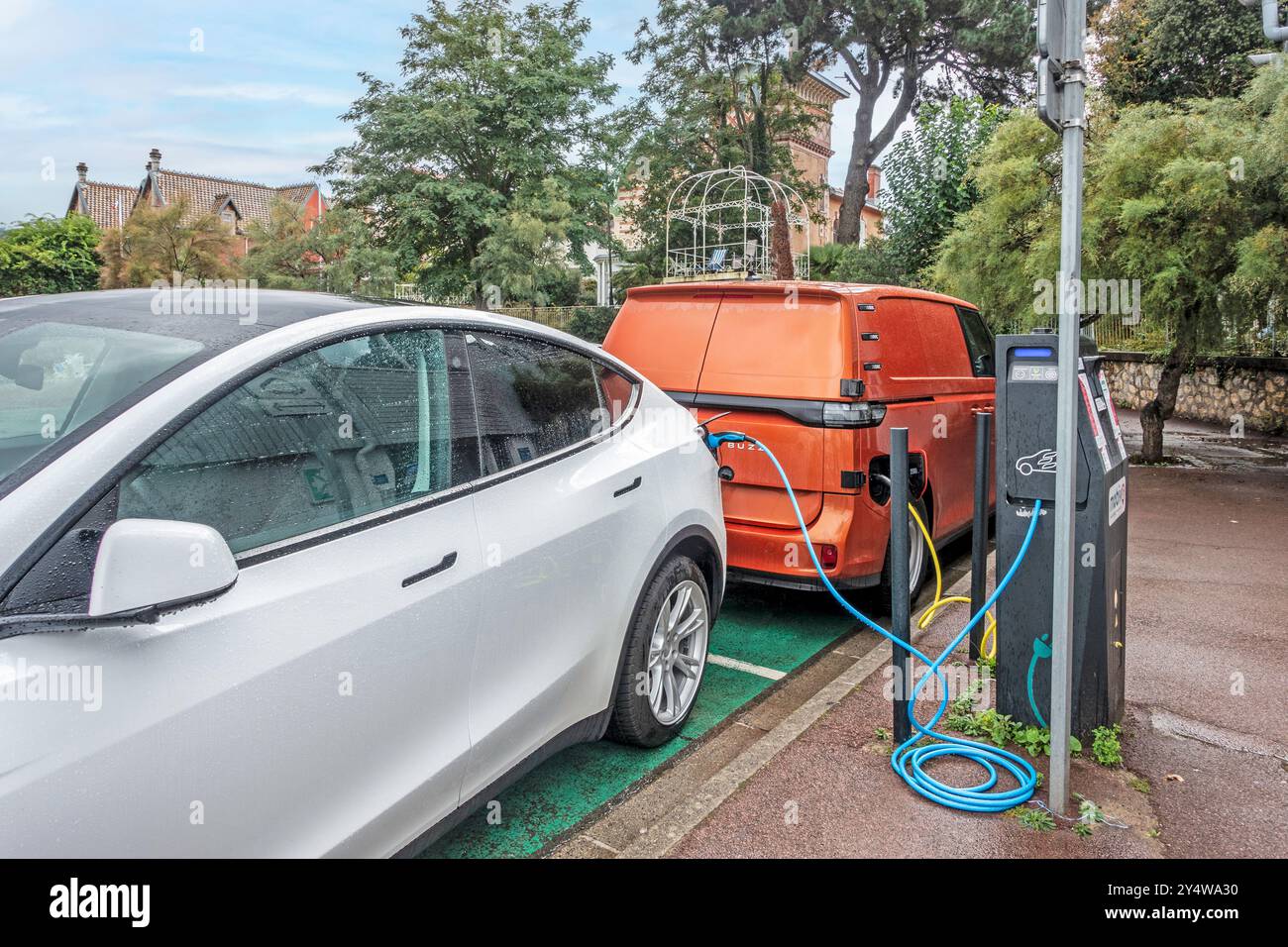 A Tesla car and a Volkswagen ID Buzz charging at a charging station in Arcachon, France. Stock Photo