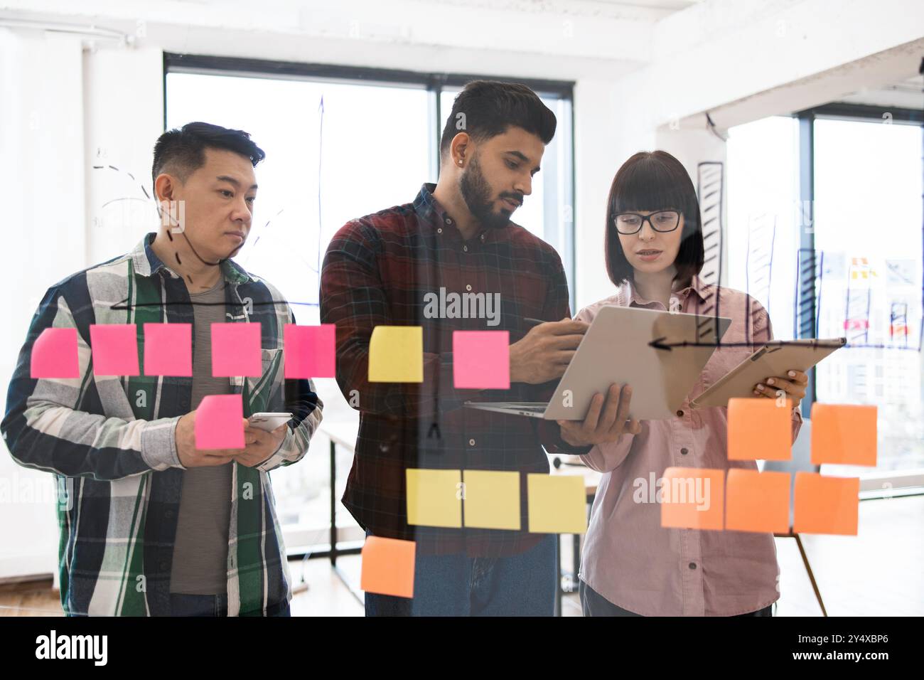 Team brainstorming session with sticky notes and digital devices Stock ...