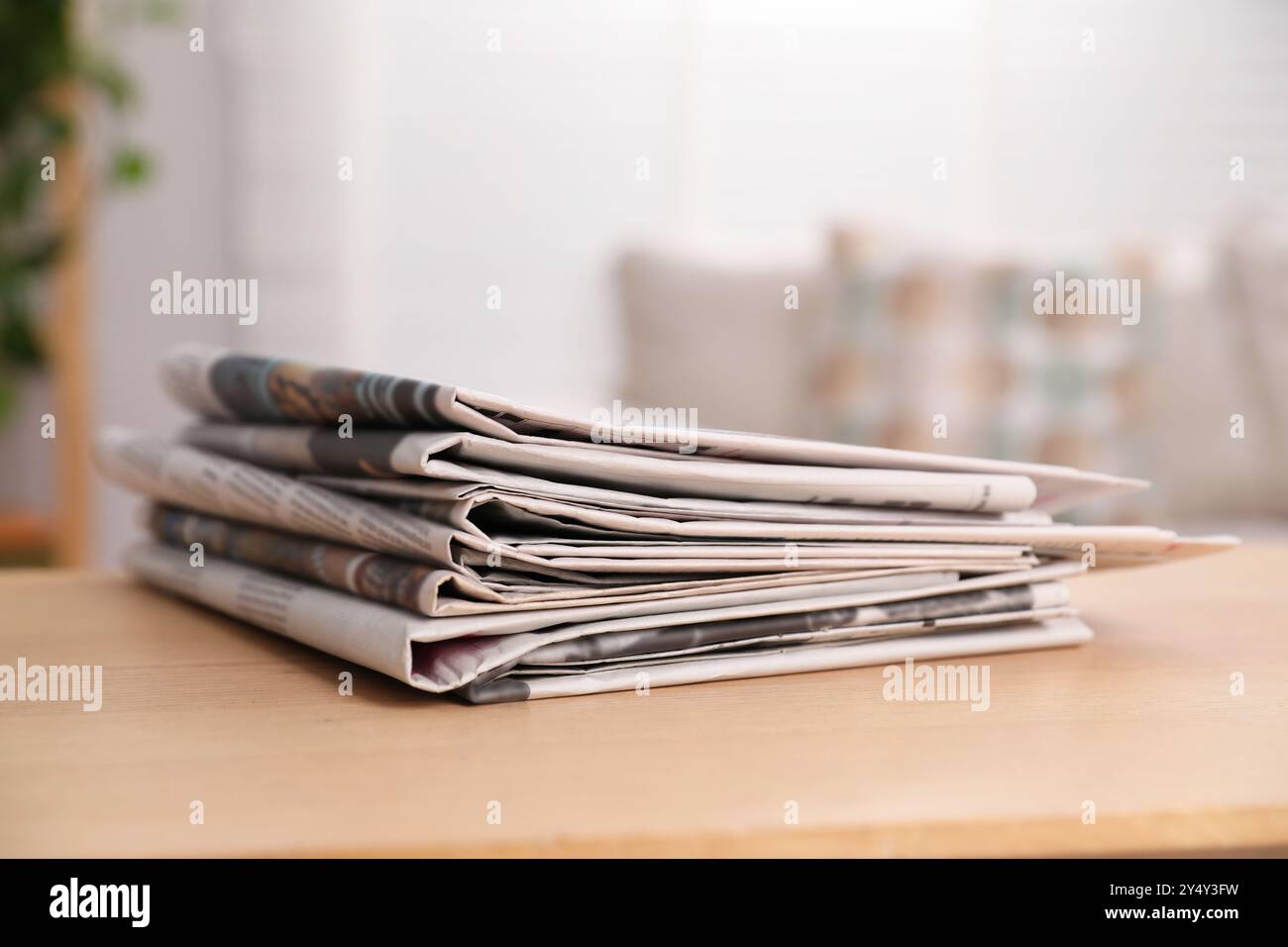 Stack of newspapers in different languages on table indoors Stock Photo