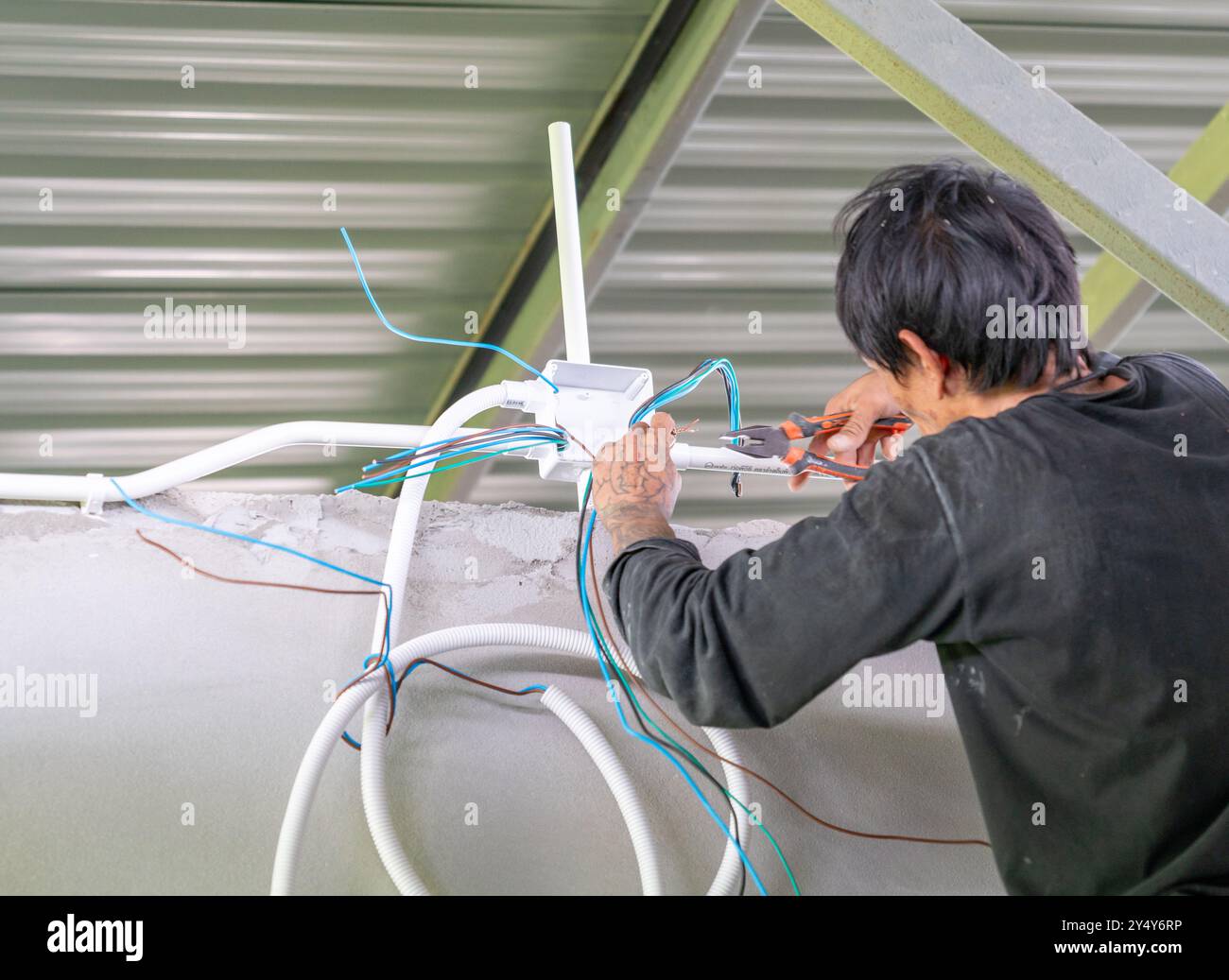 Technician splice wires with pliers in building site. Stock Photo