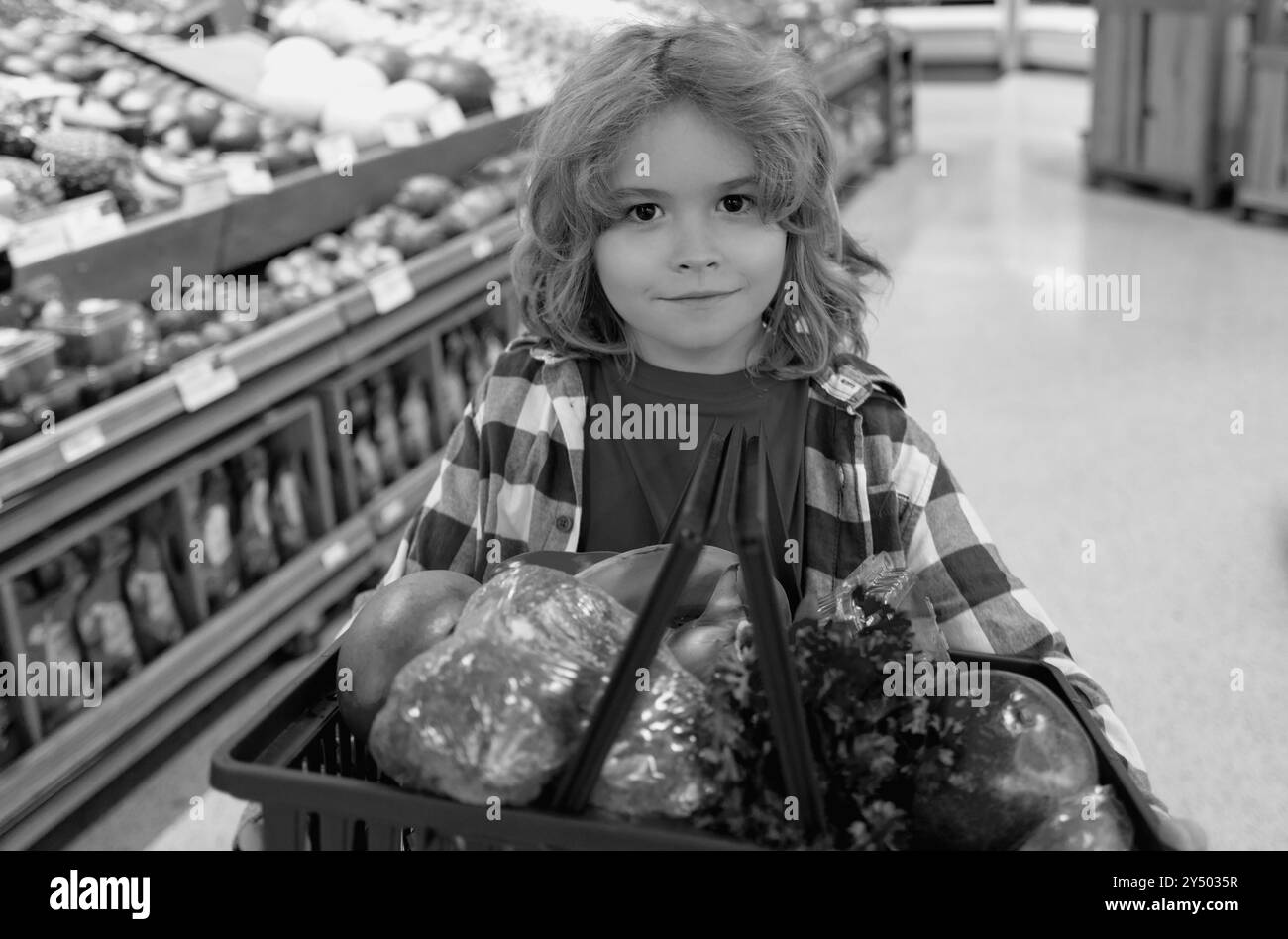 Cute child hold shopping cart full of groceries. Kid holds shopping basket. Store, shopping, sales and discounts. Little shopper. Kid holding shopping Stock Photo