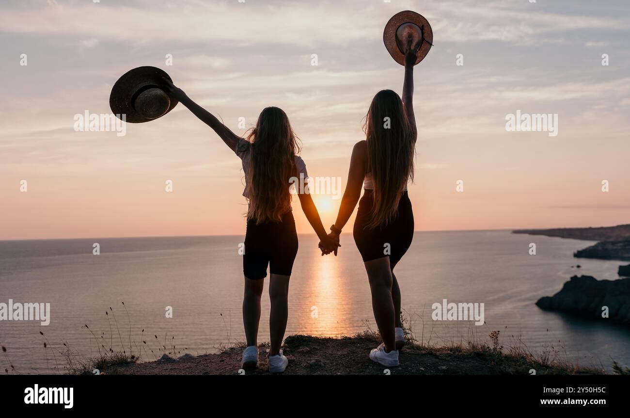Silhouettes of Two Women Holding Hands on a Cliff Overlooking the ...