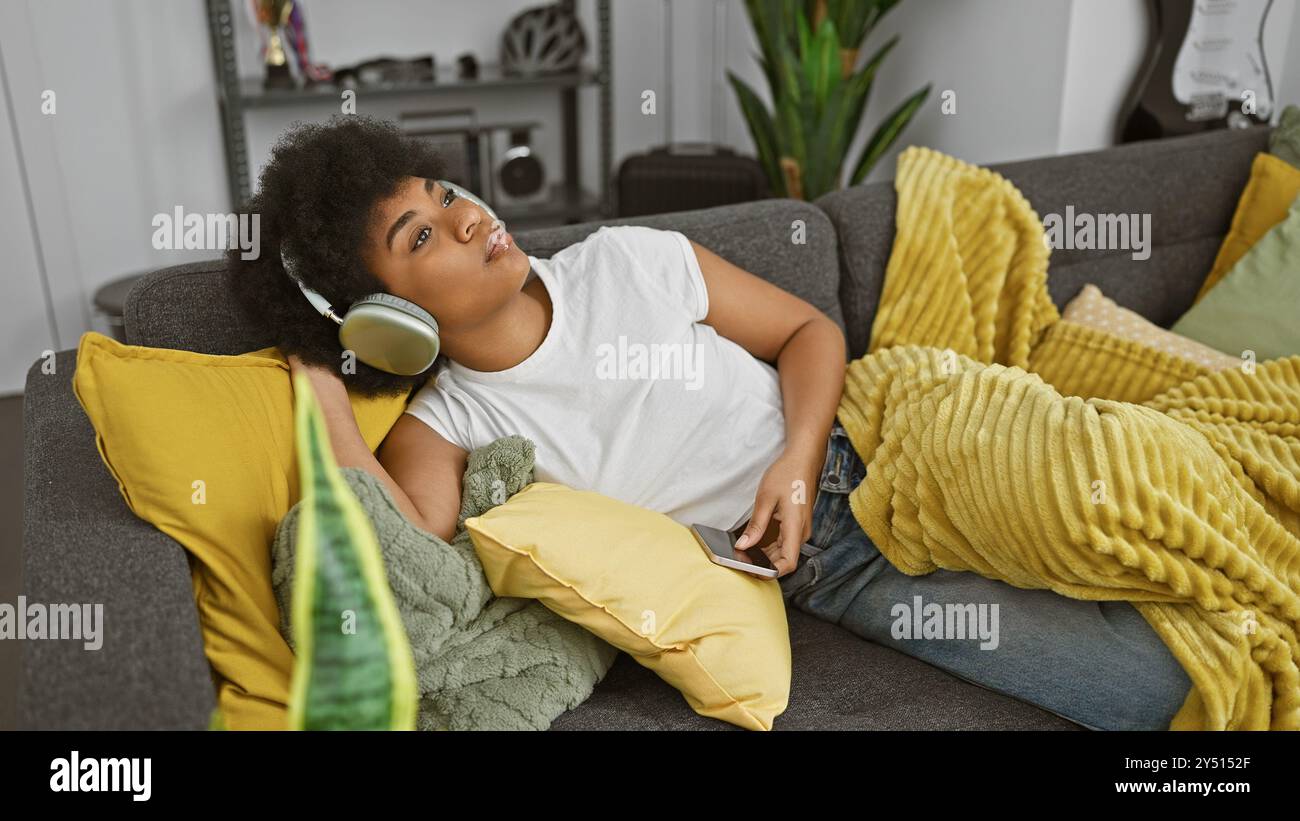 African american woman relaxing with headphones on a couch in a cozy ...