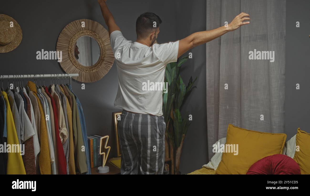Hispanic Rack A young hispanic man stretching in a bedroom with a clothing rack ...