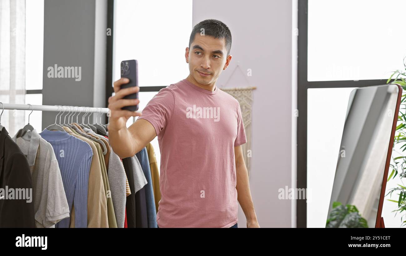 Hispanic Rack Hispanic man in casual attire takes selfie in well-lit dressing room ...