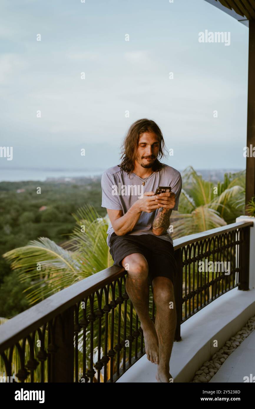 Man using smart phone while sitting on terrace. Stock Photo