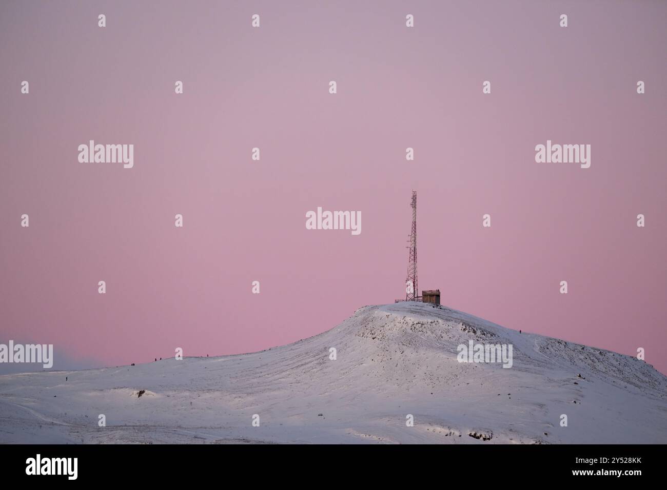 Antenna mast on snow covered hill during sundown Stock Photo