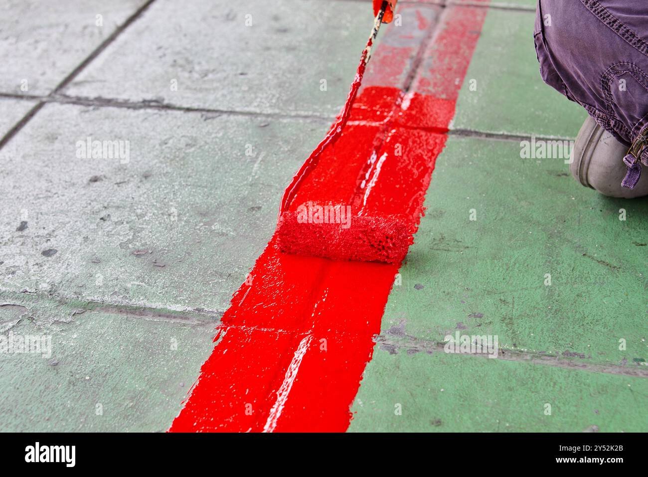 Worker using Paint roller and painting red color on footpath Stock Photo