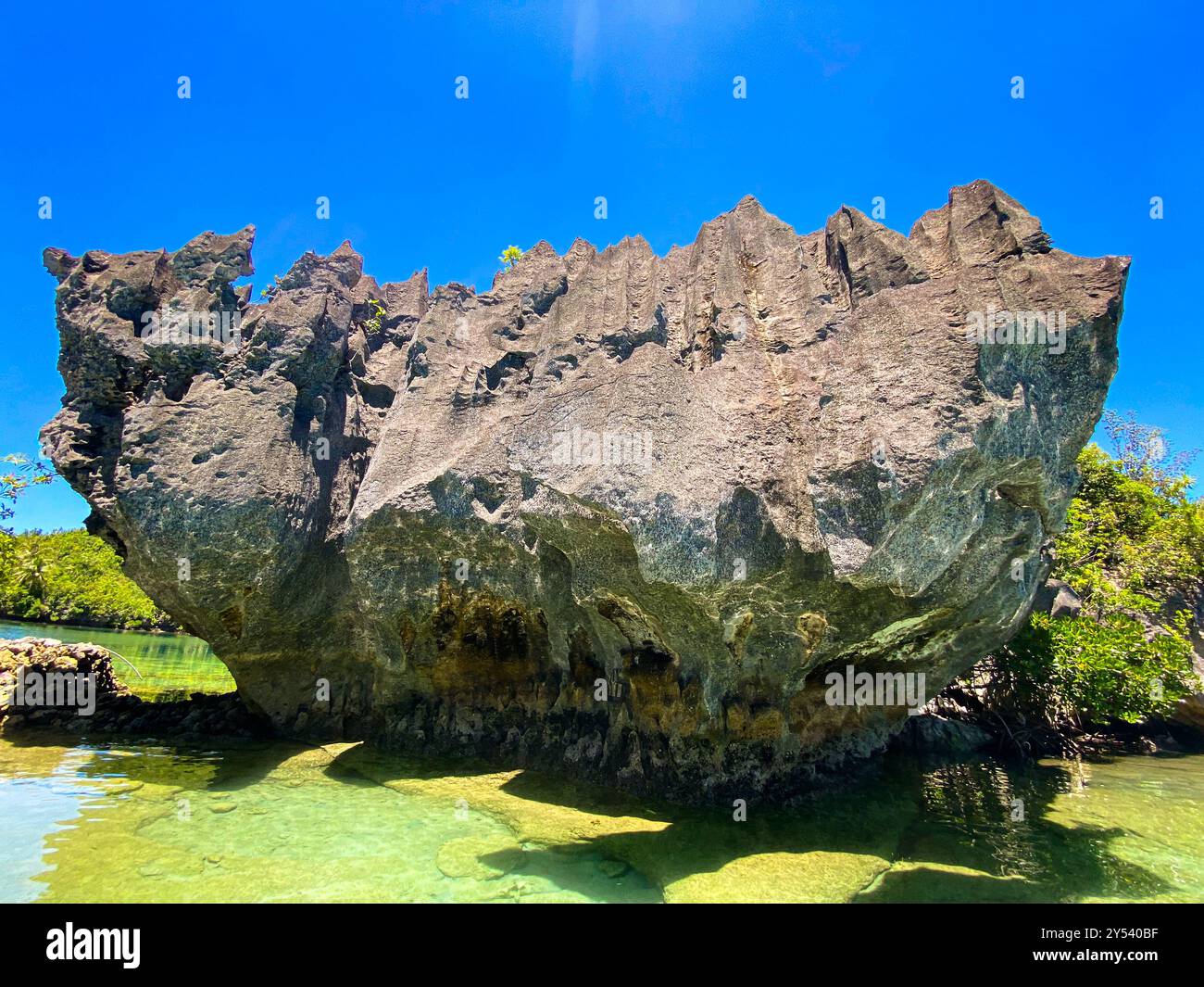Greenish sea water and big rock with beautiful formation. Tinago Island ...