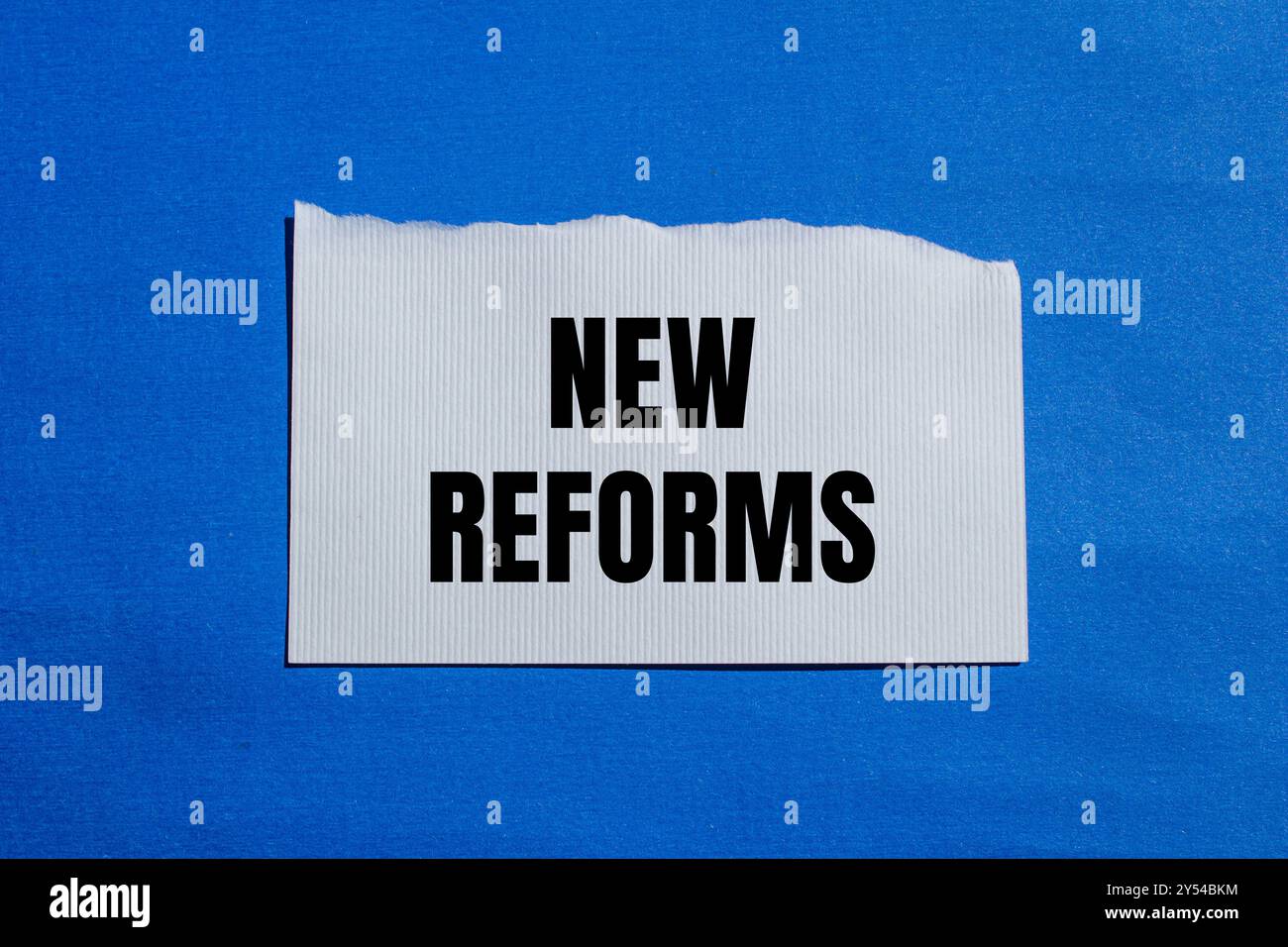 New reforms message written on ripped white torn paper piece with blue ...