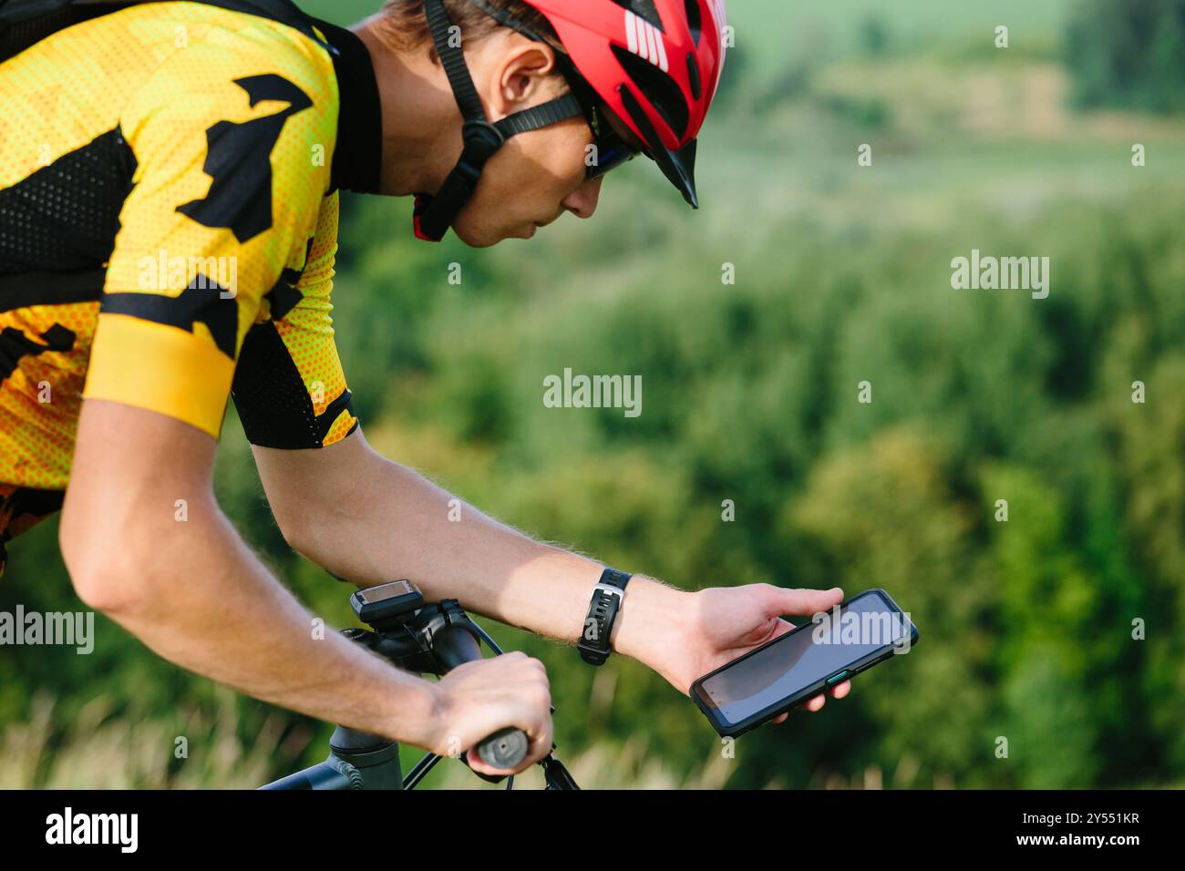 Happy male cyclist sending a text message on his mobile phone. Image of a cyclist on a mountain bike using a smartphone navigator exploring a map and Stock Photo
