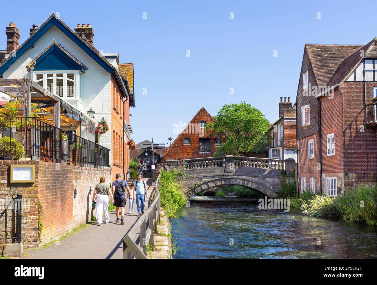 People walking by the River Itchen and The Bishop on the Bridge pub with the City Mill A restored 18th-century watermill in Winchester Hampshire UK Stock Photo