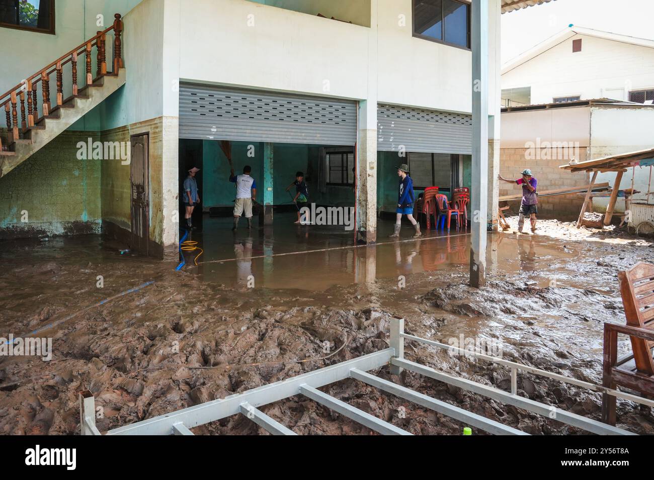 People are seen helping each other to clean a house covered by mud ...