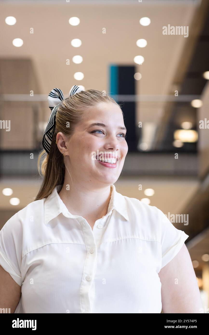 Smiling woman in business attire standing in modern office building Stock Photo