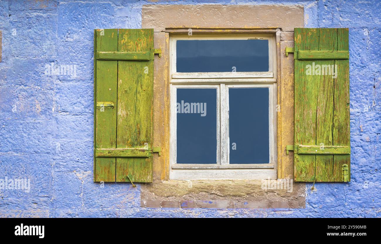 Aged wooden window and green shutters from an old german house with blueish painted wall stone Stock Photo