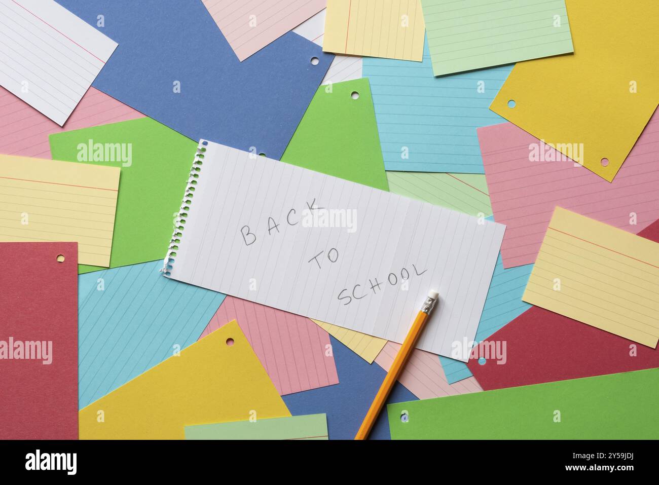 Notebook sheet with the message back to school against a background of colorful paper notes Stock Photo