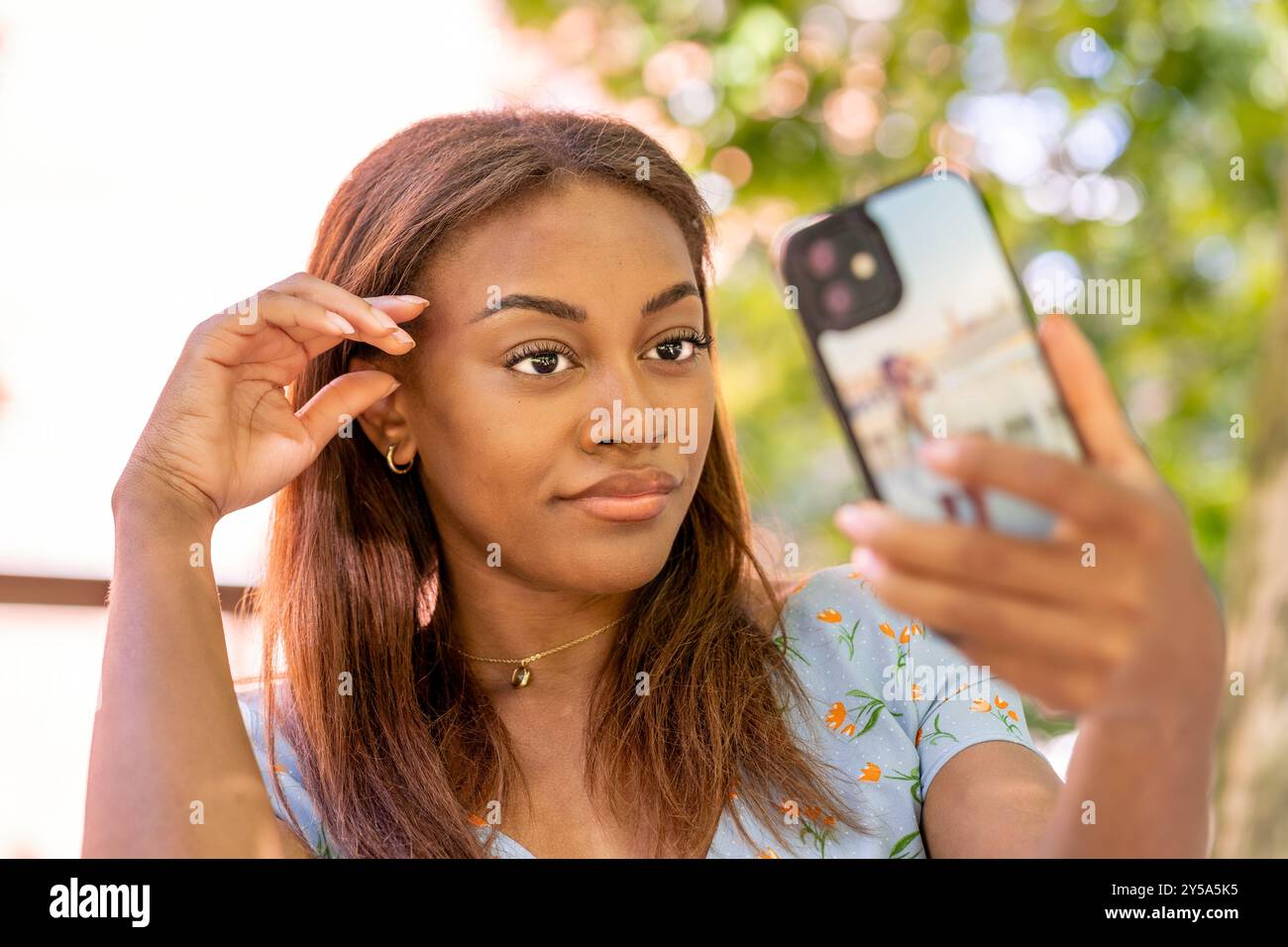 Beautiful young woman is taking a selfie with her smartphone in a park ...