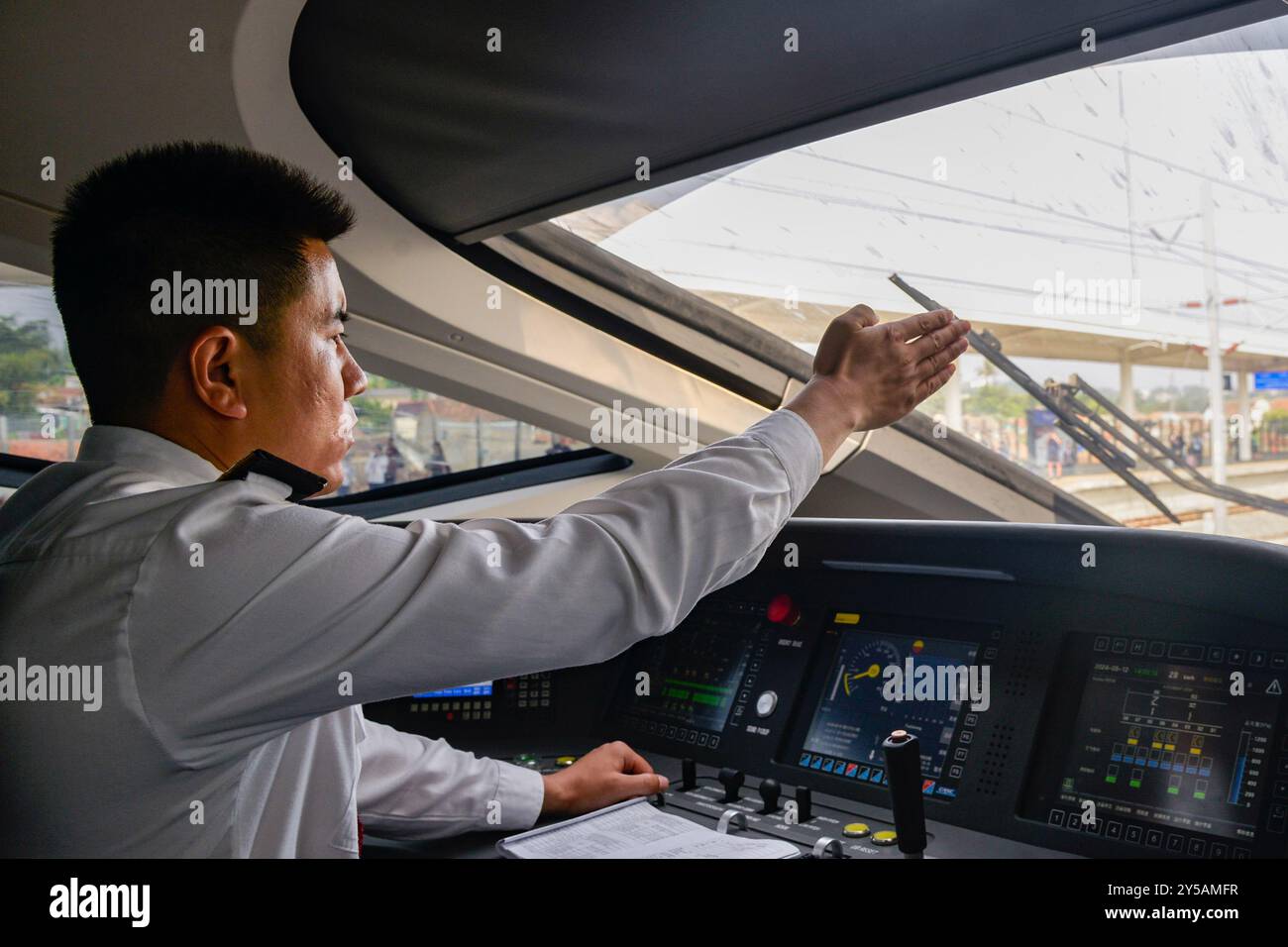 (240920) -- JAKARTA, Sept. 20, 2024 (Xinhua) -- Zhang Yue operates at the cab of a high-speed train in Bandung, Indonesia, Sept. 12, 2024. Zhang Yue, 34, is a train driver for the Jakarta-Bandung high-speed railway (HSR). He came to Indonesia in February 2023 for joint debugging, trial operation, and talent training of the HSR. The HSR, the first of its kind in Southeast Asia, boasts a design speed of 350 kilometers per hour, and connects Halim station in Jakarta to Tegalluar station in Indonesia's fourth largest city Bandung of West Java province, cutting the travel time between the two citi Stock Photo