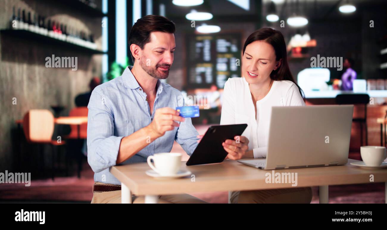Couple Shopping Online On Laptop In Cafe Stock Photo