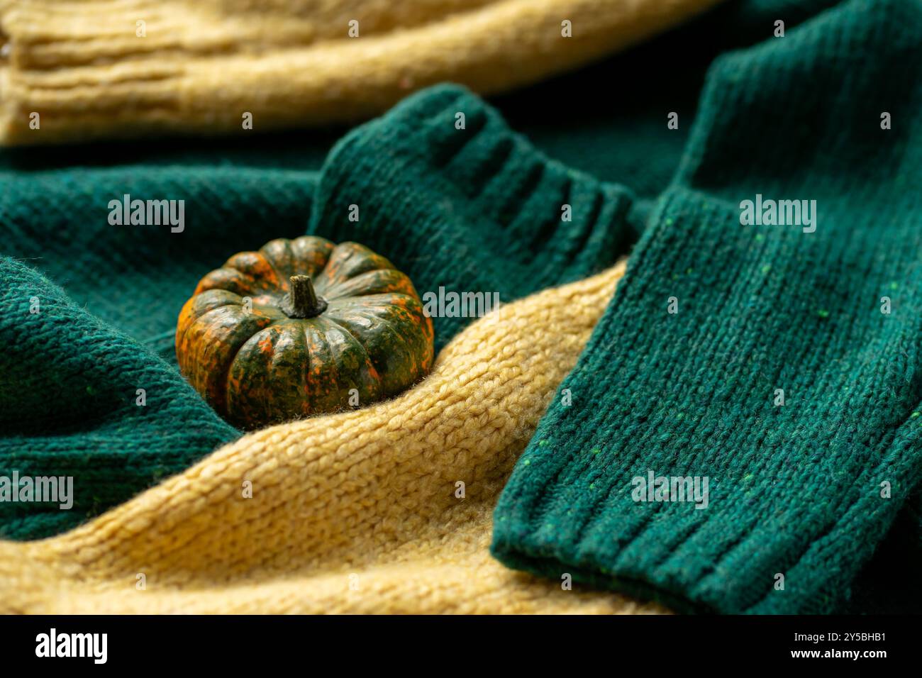Orange pumpkin near a stack of knitted sweaters on a knitted blanket. Stock Photo