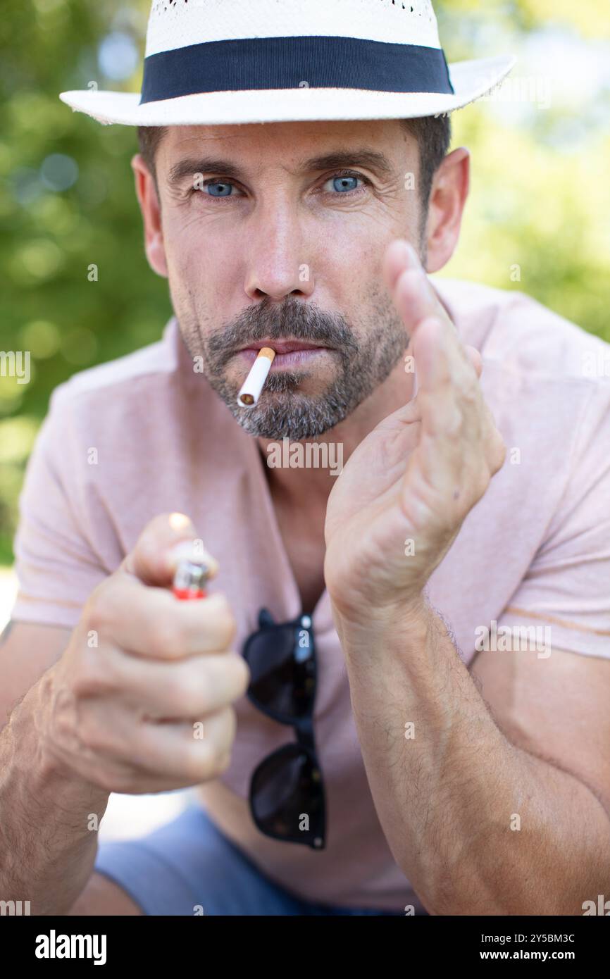 man outdoors poised to light a cigarette Stock Photo