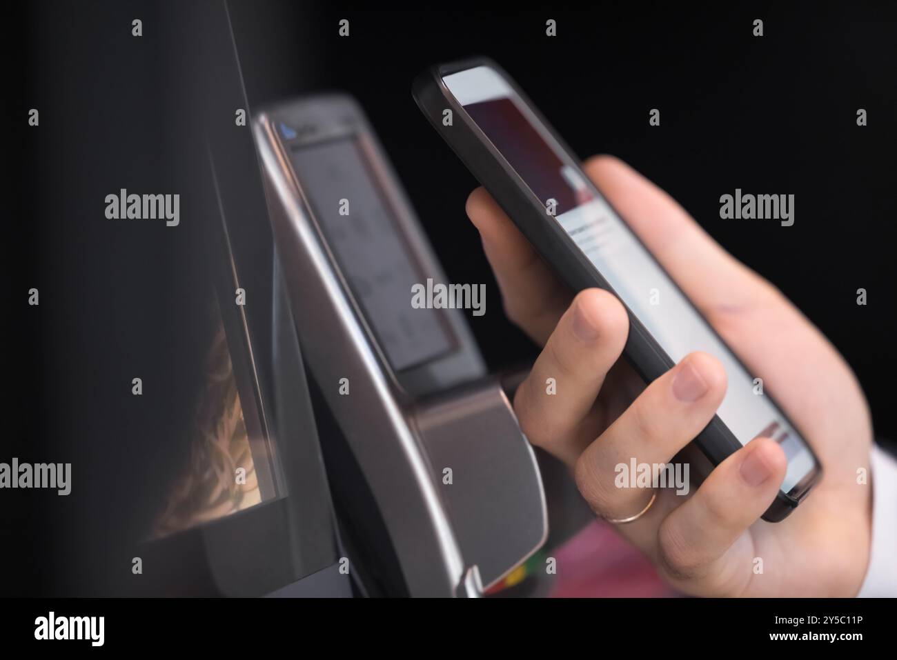 Male hand holding smartphone at POS terminal device Stock Photo