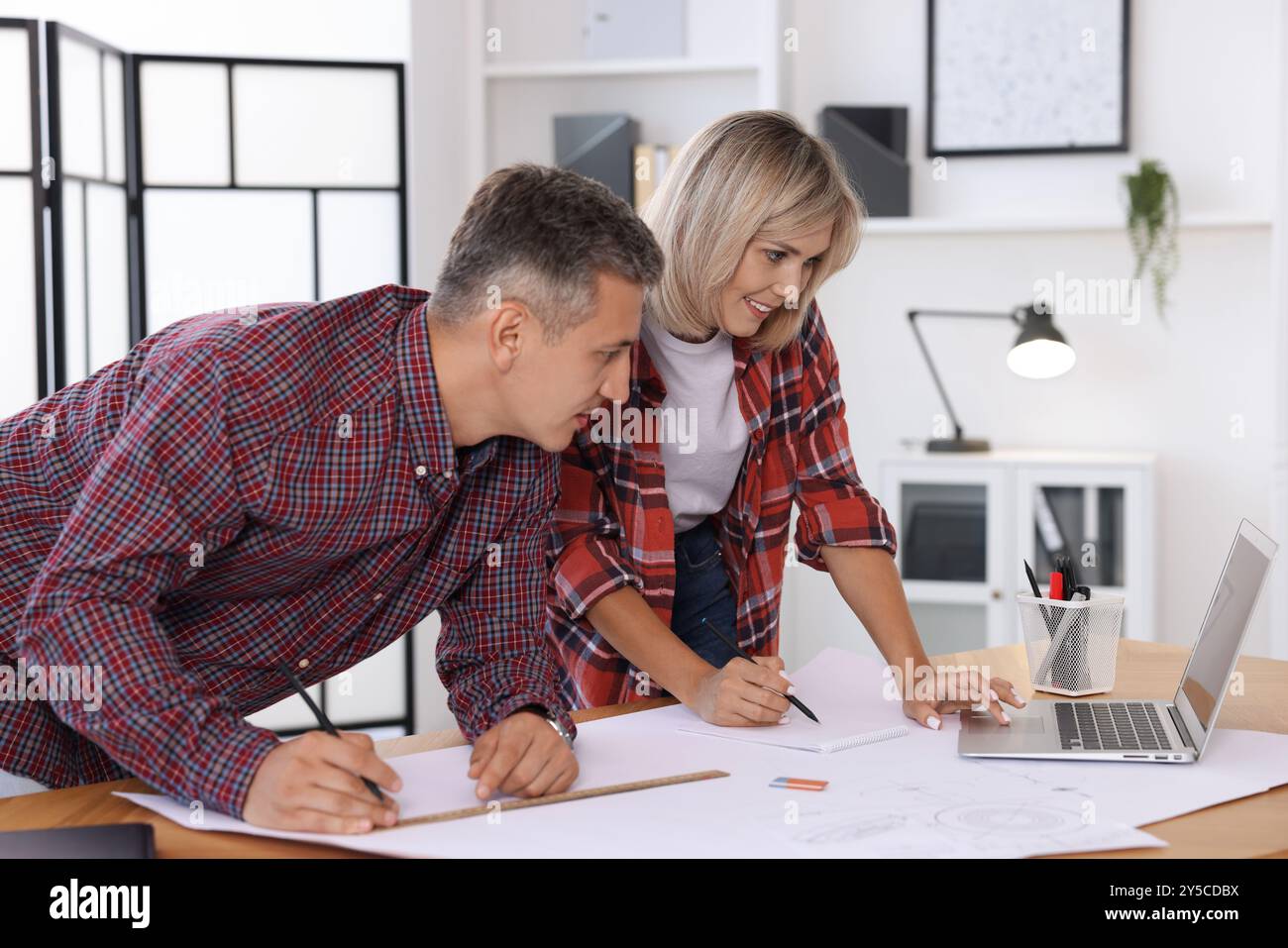 Architects making engineering drawing at wooden table in office Stock Photo