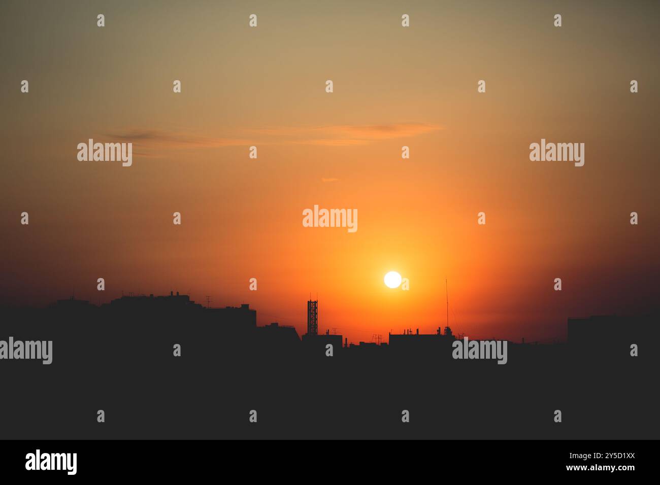 The rising sun casts a bright glow over the city's silhouette, turning ...