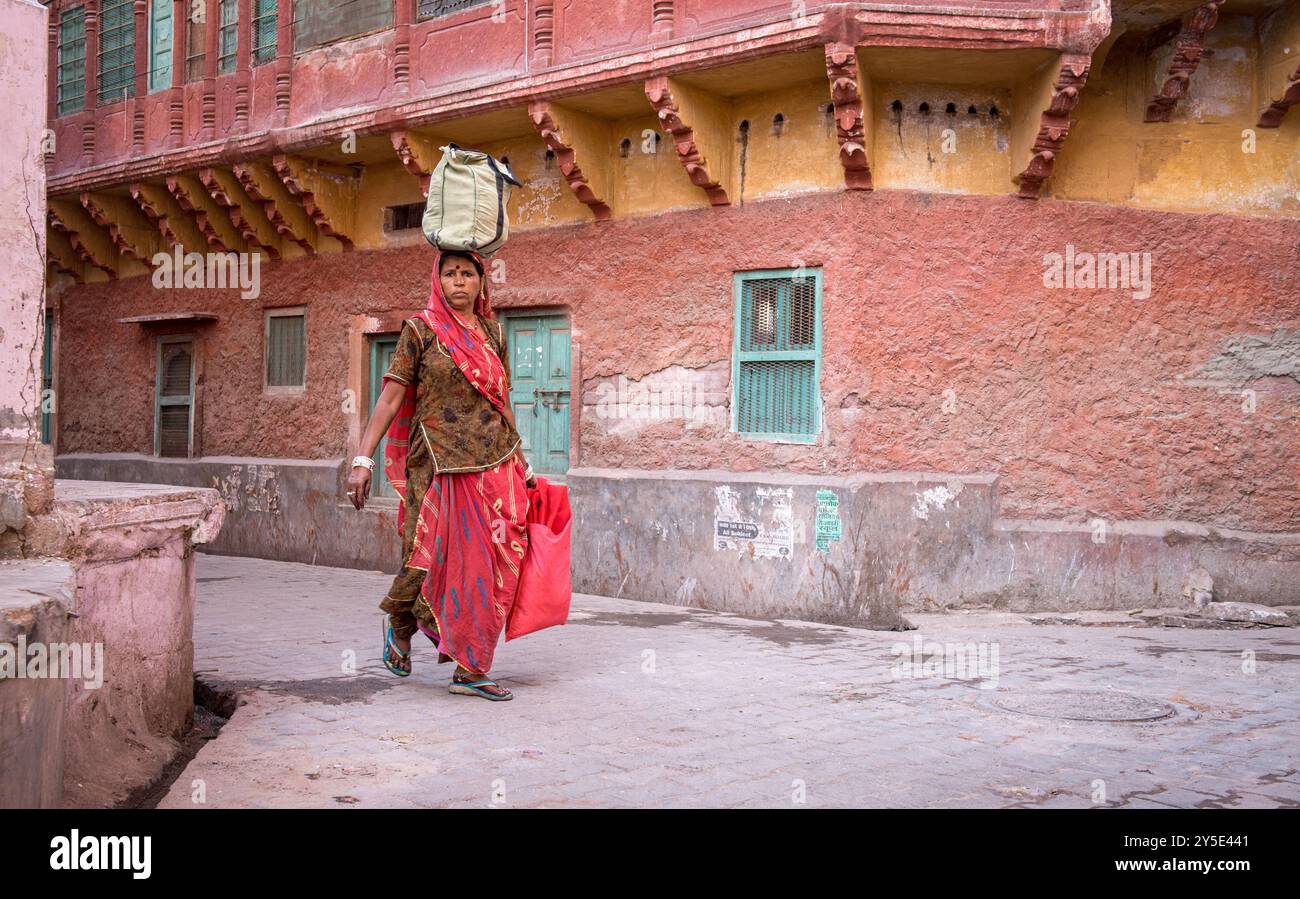 indian-woman-carrying-bags-walking-in-traditional-village-stock-photo