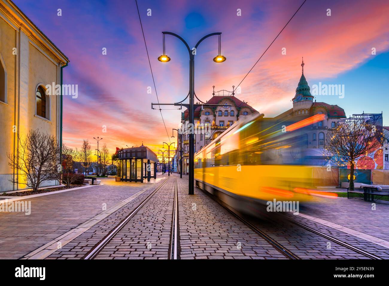 Oradea, Romania. Tram station motion blur in Union Square, beautiful city architecture of Crisana, Transylvania, twilight colored sky. Stock Photo
