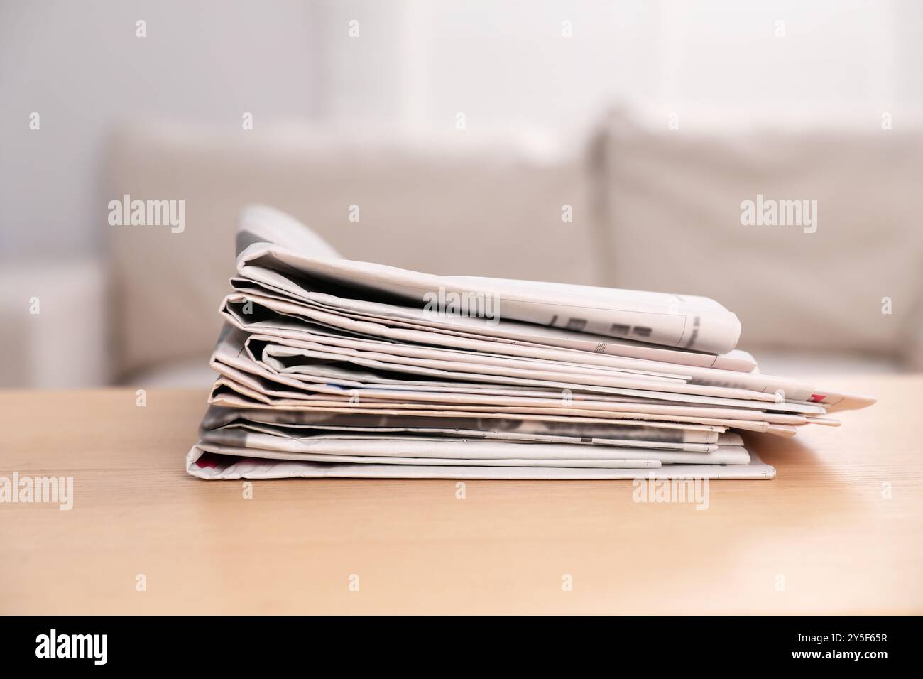 Stack of newspapers in different languages on table indoors Stock Photo