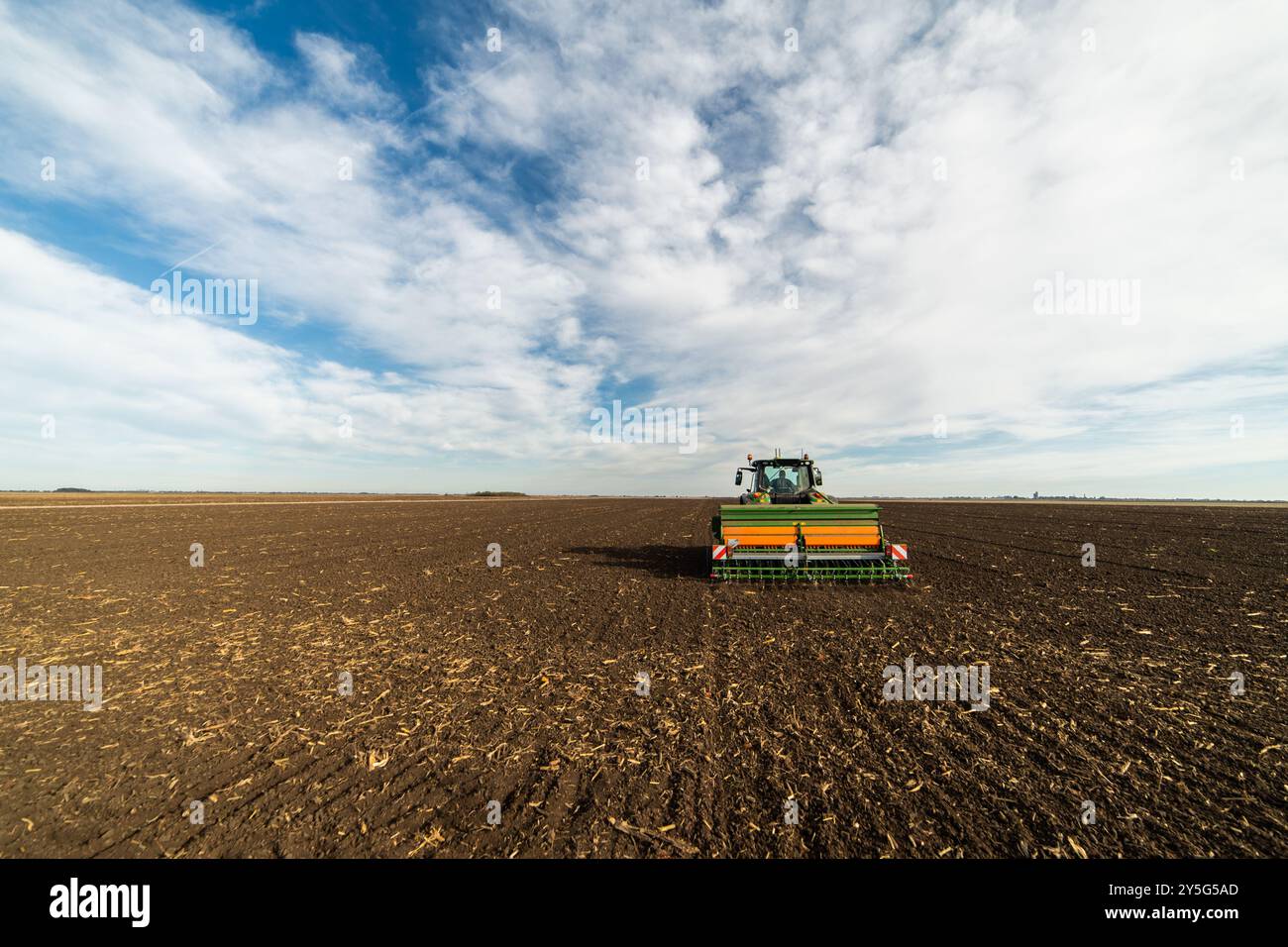 Farmer with tractor seeding - sowing crops at agricultural field ...