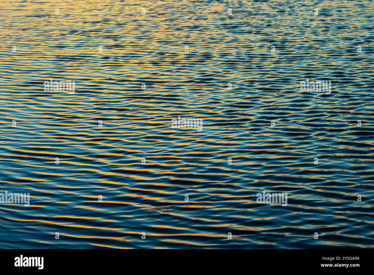 Soft waves create textured patterns under the warm glow of evening light. Stock Photo