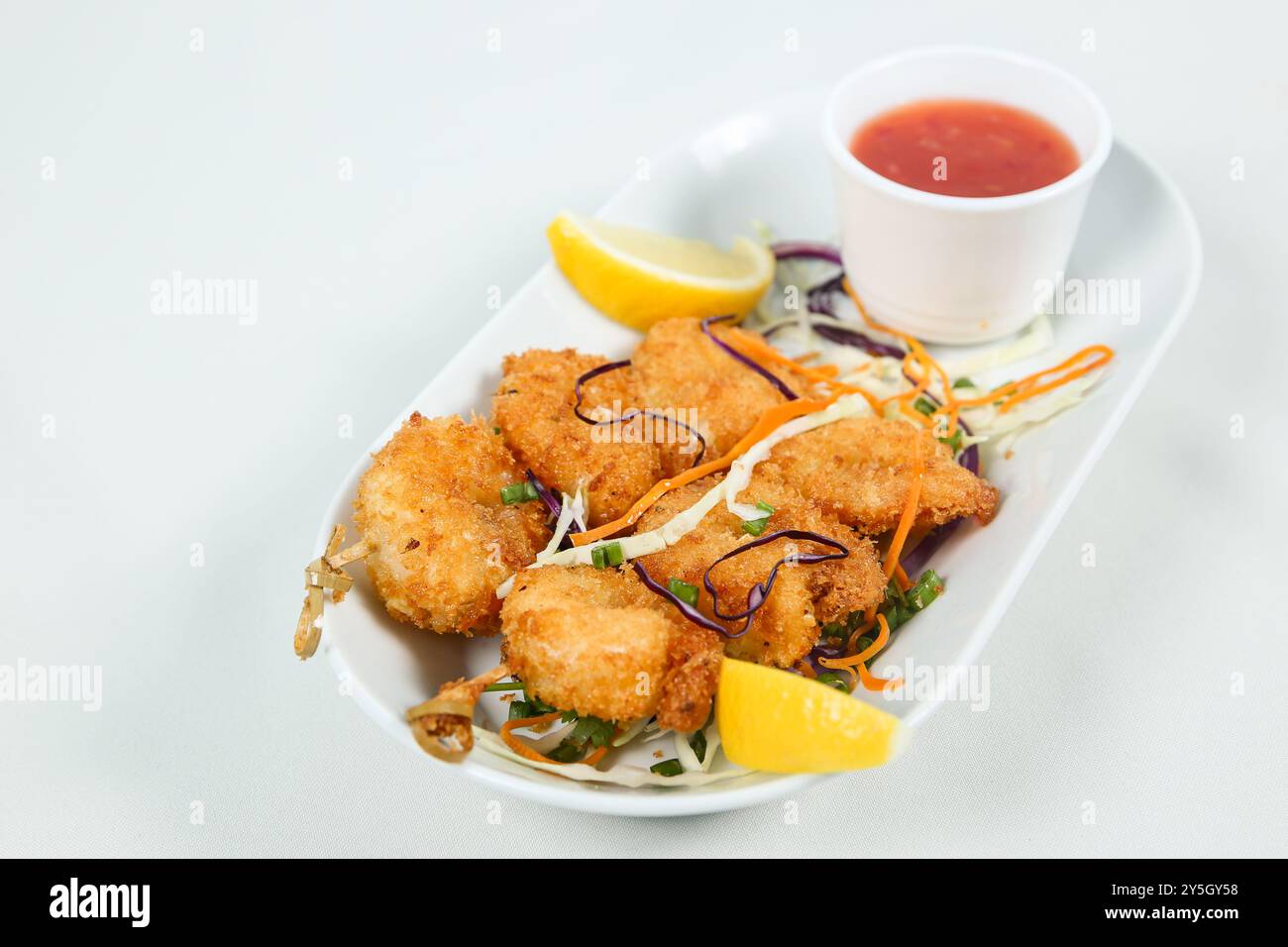Golden fried shrimp served with slices of fresh lime and dipping sauce, garnished with salad Stock Photo