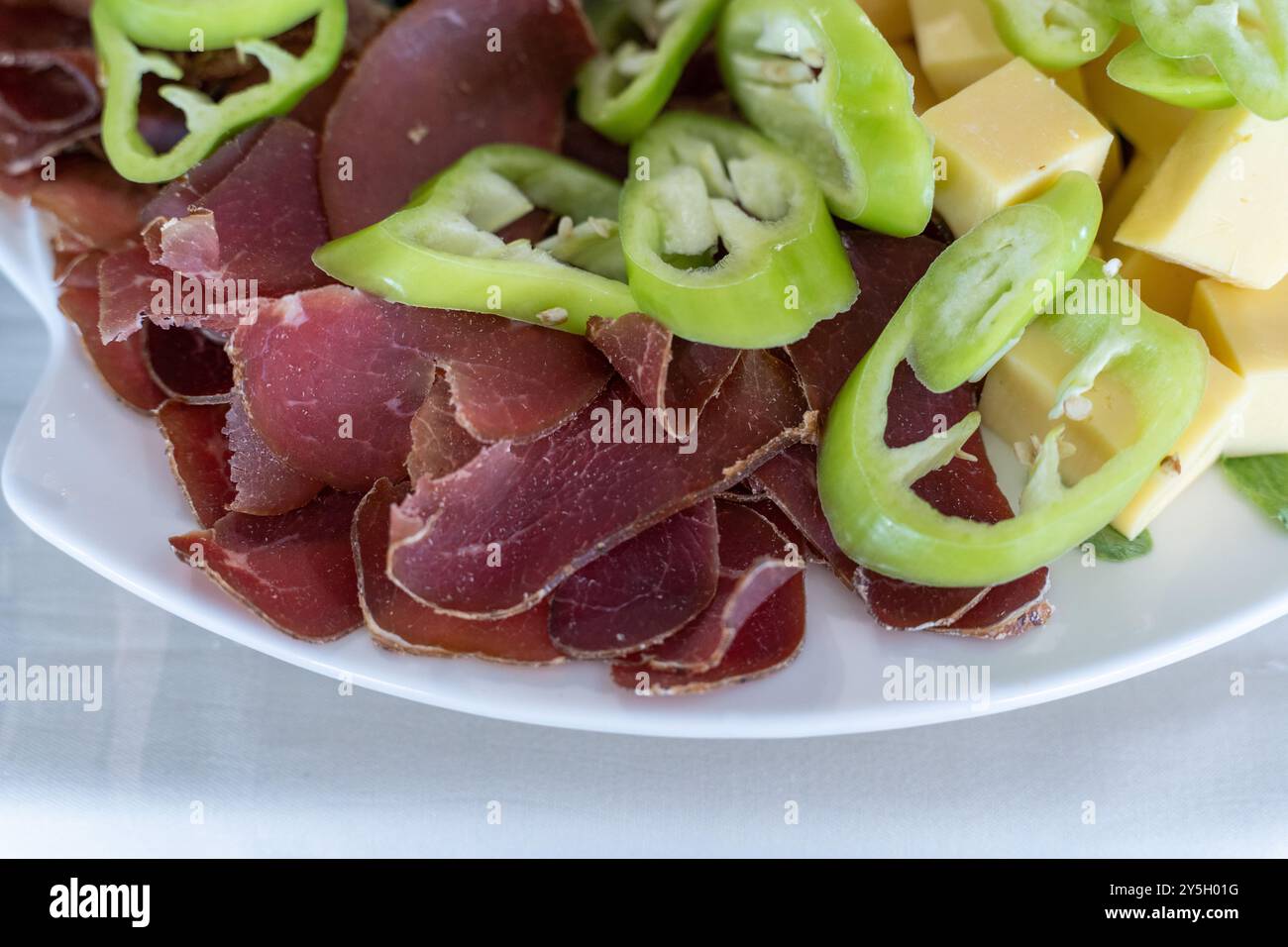 Cured Meat Selection with Yellow Cheese and Green Peppers – Starters Snack Plate. Stock Photo